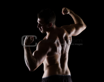 Strong sports man showing muscular back on black