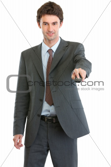 Smiling businessman using TV remote control