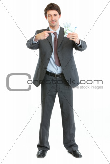 Full length portrait of businessman pointing on packs of euros