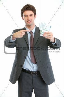 Smiling businessman pointing on packs of euros