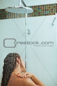 Long hair woman taking shower under water jet. Rear view