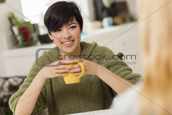Mixed Race Young Attractive Woman Socializing with Friend in Her Kitchen.
