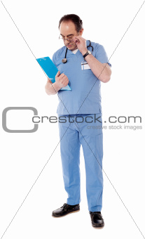 Experienced doctor with stethoscope, reading reports