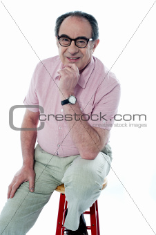 Old man sitting on stool, posing in style