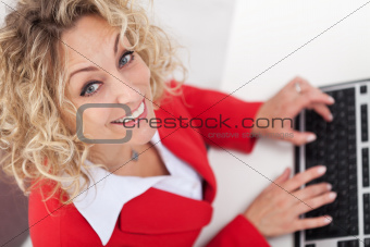 Woman in office typing on keyboard - smiling