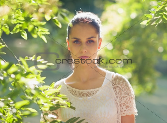 Portrait of young woman standing in foliage