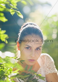 Portrait of young woman in foliage