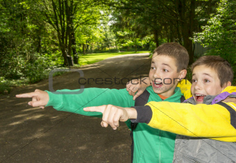 Portrait of two surprised boys, tweens are pointing and hugging 