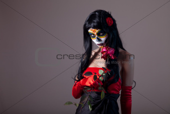 Sugar skull girl holding red rose 