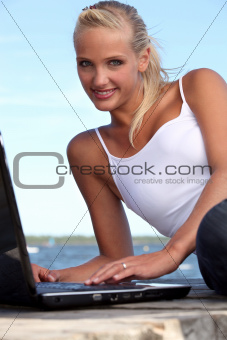 Attractive woman using her laptop on a pontoon