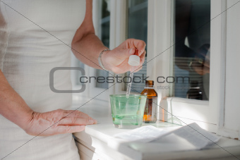 Health issues, old woman taking prescription drugs and drinking 