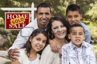 Happy Hispanic Family in Front of Sold Home for Sale Real Estate Sign.