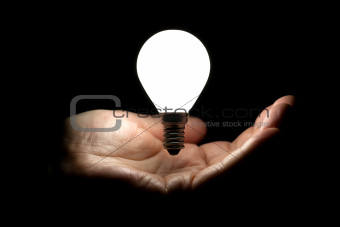 Floating lightbulb above hand on black background
