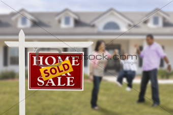 Sold Real Estate Sign and Playful Hispanic Family in Front of House.