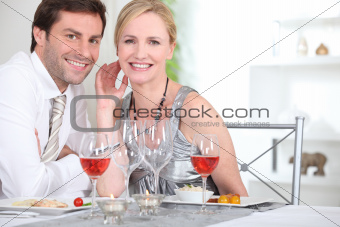 An elegant couple having dinner and smiling at us.