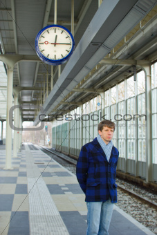 A man waiting for a train under a clock