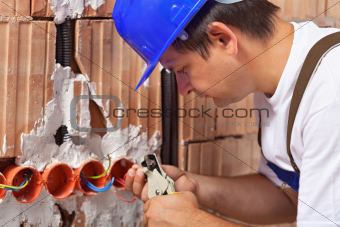 Worker installing electrical wires in building wall