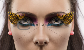 girl with feathered makeup looks in to the lens