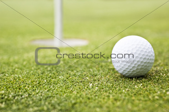 Golf ball on a putting green with the flag in background