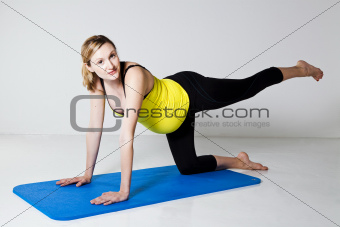 Pregnant woman exercising on mat
