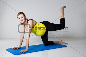 Pregnant woman exercising on mat