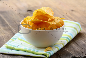 potato chips in a white bowl on a wooden table