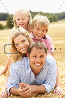 Family Relaxing In Summer Harvested Field