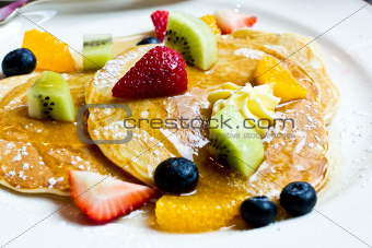 Fresh fruit pancakes with honey syrup.