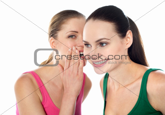 Young beautiful girl whispering secret in her friends ear