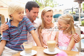 Young Family Enjoying Cup Of Coffee In Caf Together