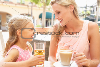 Mother And Daughter Enjoying Cup Of Coffee And Juice In Caf Together
