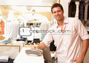 Male Sales Assistant At Checkout Of Clothing Store