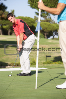 Male Golfer On Golf Course Putting On Green