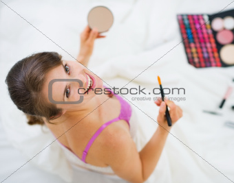 Smiling girl applying makeup. Upper view