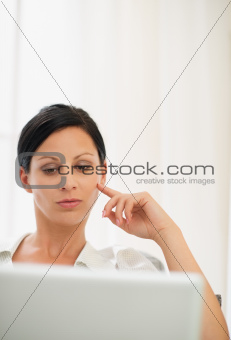 Portrait of thoughtful young woman working on laptop