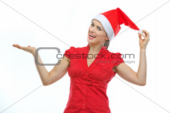 Happy young woman in Christmas hat showing something on empty palm