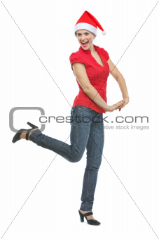 Cheerful young woman in Santa hat dancing