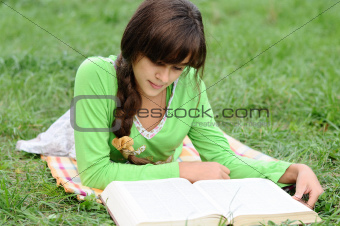 Girl reading a book lying on the grass