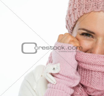 Closeup on woman in knit winter clothing closing face with scarf