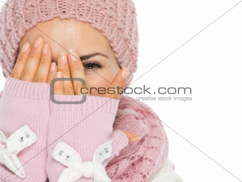 Woman in knit scarf, hat and mittens hiding behind hands