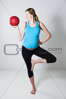Pregnant woman exercising with exercise ball while balancing