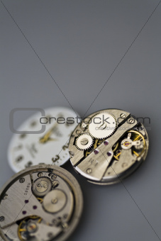 Old metal mechanical clock with gear wheels on a gray background