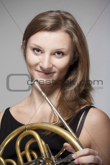 young female musician with concert french horn in black dress