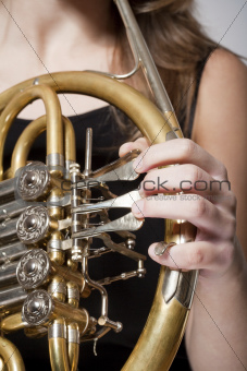 detail of a female musician«s fingers playing concert french horn 