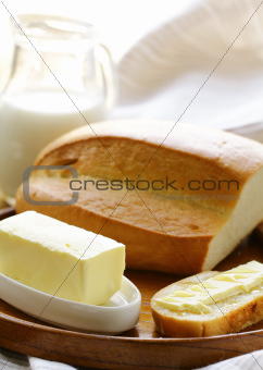 butter,  loaf of white bread and milk on wooden plate