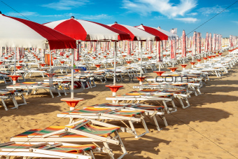 red and white umbrellas and sun loungers on the sandy beach