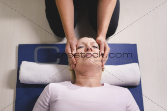 Young therapist doing reiki therapy to senior woman