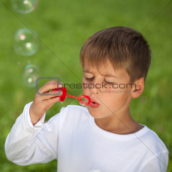 Boy having fun with bubbles on a green meadow