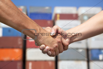 two business man handshaking before stack of containers