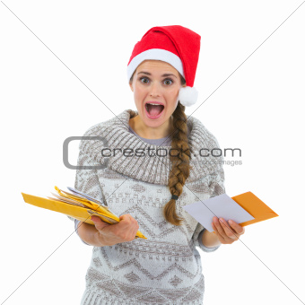 Shocked woman in Santa hat surprised by lots of Christmas letters